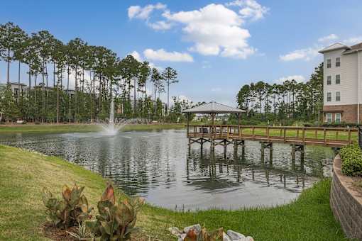 A fountain in the middle of a lake with a bridge in the background.