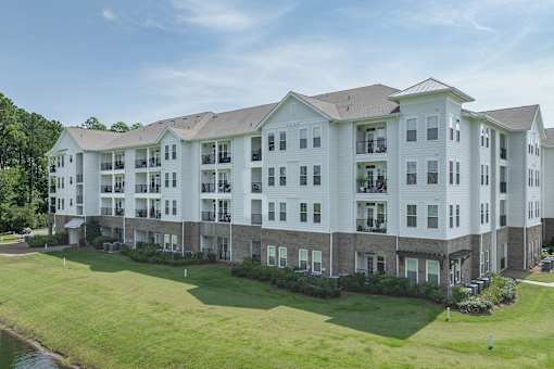 A large white apartment building with a grassy lawn in front.
