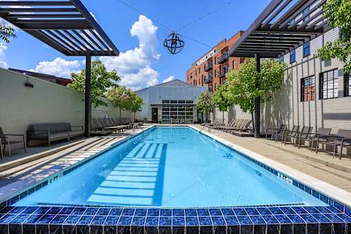 A blue tiled pool surrounded by a metal fence and trees.