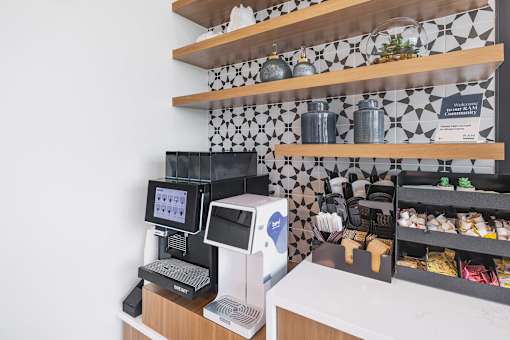 A white and black checkered tile backsplash behind a counter with a cash register and a digital menu.