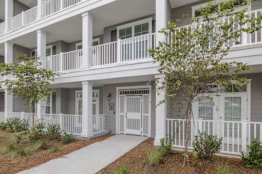 A white building with a tree in front.