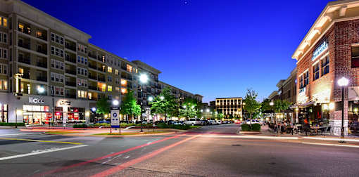 A city street at night with buildings on either side and cars driving down the road.