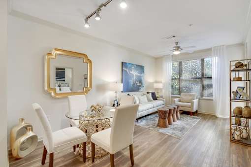 A living room with a glass table and white chairs.