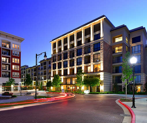 A modern apartment building with a lit walkway in front.