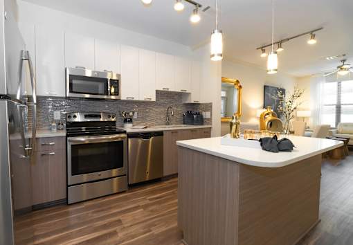 Dog-Friendly Luxury Apartments in Atlanta, GA - 1105 Town Brookhaven - Kitchen with Hardwood Floor, Stainless Steel Appliances, Two-Tone Cabinetry, and Island with Pendant Lighting.