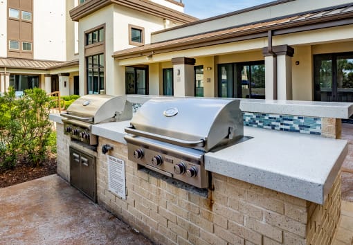 a large stainless steel grill sits on a stone counter outside of a building