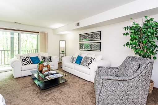 A living room with a white couch, a grey armchair, and a glass coffee table at Winchell Way Apartment , Kalamazoo, 49008