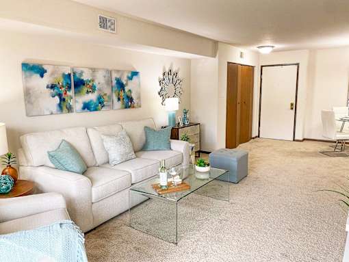 A living room with a white couch, a glass coffee table, and a painting on the wall at Winchell Way Apartment , Kalamazoo, 49008