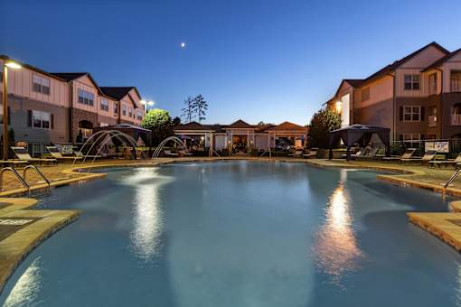 A large swimming pool surrounded by apartment buildings at dusk.