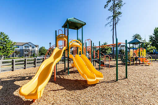 A playground with a yellow slide and a green roofed structure.