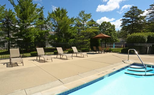 a swimming pool with chaise lounge chairs and a poolside umbrella  at Pheasant Run, Saginaw, MI