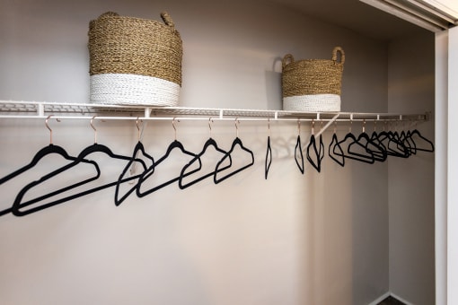 a closet with a coat rack and hooks and a pair of baskets on the wall