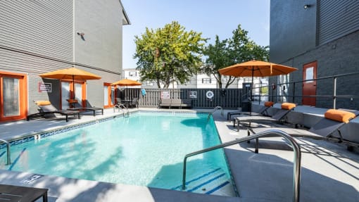 a pool with lounge chairs and umbrellas at the district flats apartments in lenexa
