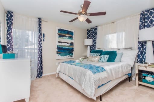 One, Two, and Three-Bedroom Apartments in Stockbridge, GA - Avenue 33 - Spacious Bedroom with Carpet Flooring, a Ceiling Fan, and Windows with Blinds.