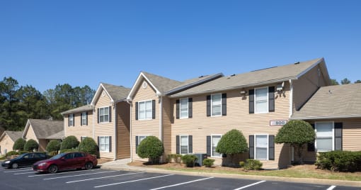 Atlanta, GA Apartments - City Park - Exterior of Apartments with Manicured Bushes, Walking Path, and Parking Lot.