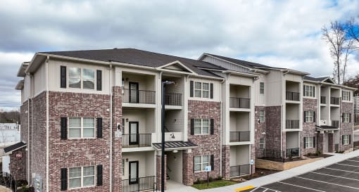 A modern red-brick apartment building with balconies and black railings in West Knoxville, TN.