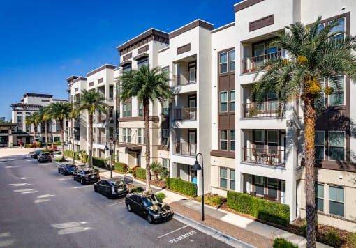 an apartment building with palm trees and cars parked in front of it