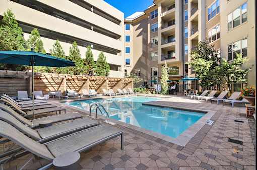 A large swimming pool surrounded by sun loungers and umbrellas.