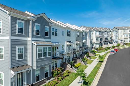 A row of modern townhouses with a car parked on the street.