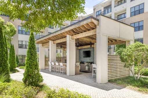 One Bedroom Luxury Apartments in Decatur, GA - Reserve Decatur - Outdoor Grilling Station With Mounted TV, Multiple Grills, High Chairs, and Lush Landscaping.