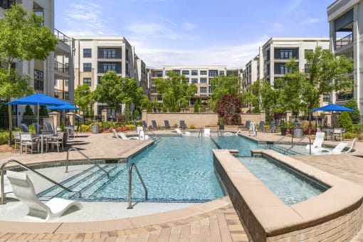 High-End Apartments in Decatur, GA - Reserve Decatur - Saltwater Swimming Pool With Sunning Ledges, Umbrellas, Tables and Chairs, and Lush Landscaping.