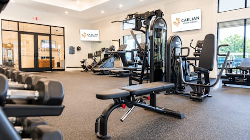 A gym with a variety of equipment including dumbbells, weight machines, and benches.