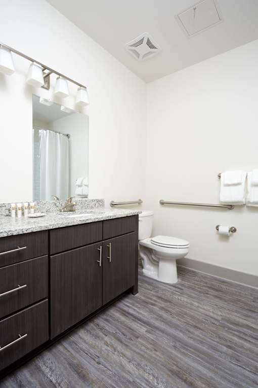 A bathroom with a toilet, sink, and mirror.