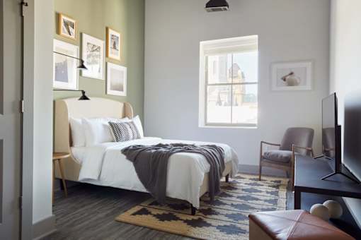 A bedroom with a large bed and a chair.