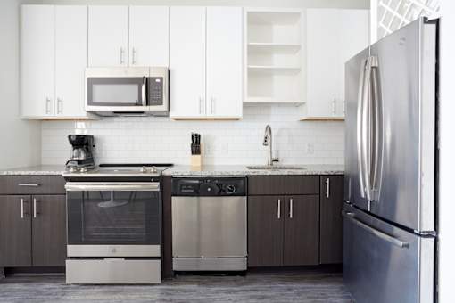 A modern kitchen with a stainless steel refrigerator and a white tile backsplash.