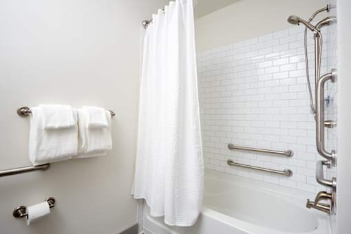 A white bathroom with a white shower curtain and a white bathtub.