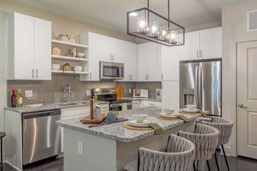 A kitchen with a granite countertop and stainless steel appliances.