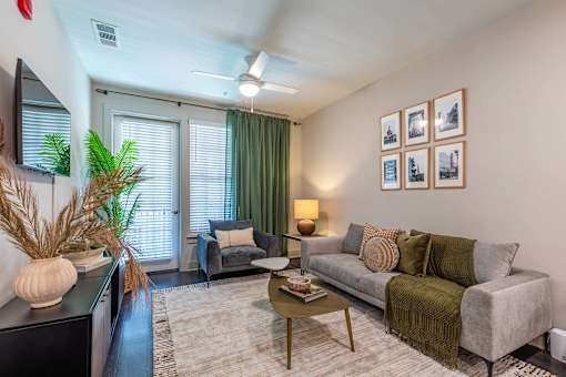 A living room with a grey couch, a coffee table, and a wall with framed pictures.