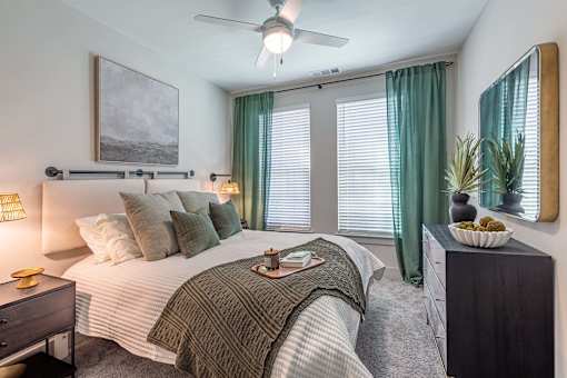 A bedroom with a bed, nightstand, and a ceiling fan.