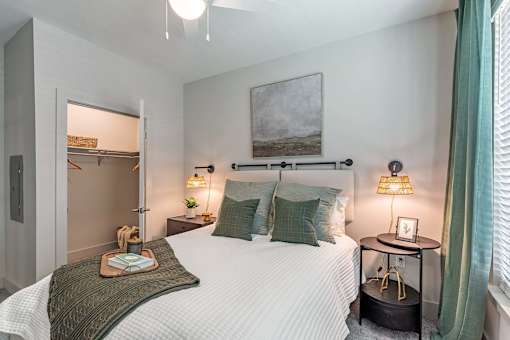 A bedroom with a large bed, a nightstand with a lamp, and a painting on the wall.