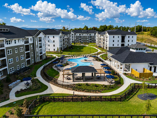 A large apartment complex with a pool and a fenced in area.