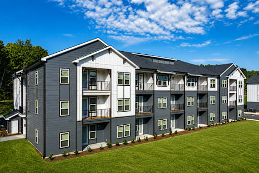 A large apartment complex with multiple balconies and a green lawn in front.