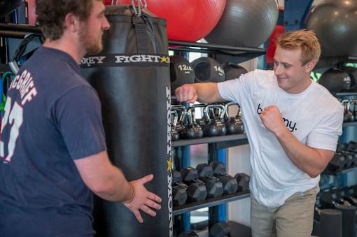 A man in a white t-shirt is punching a punching bag in a gym.