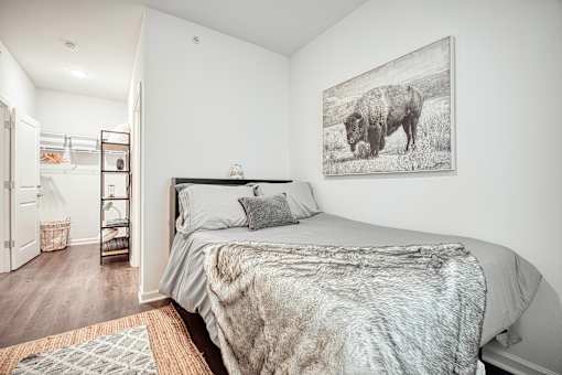 A bedroom with a bed, a wardrobe, and a painting of a bison on the wall.