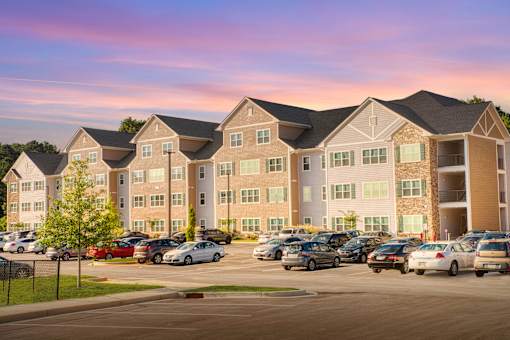 A large apartment complex with a parking lot in front.