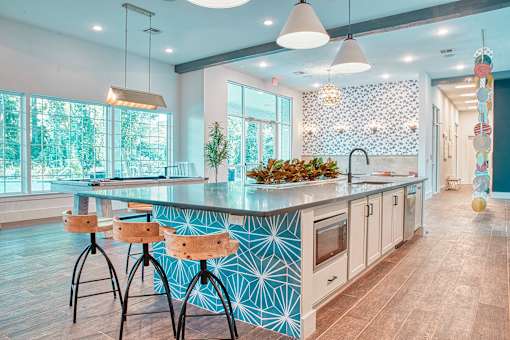 A kitchen with a blue and white patterned island and wooden bar stools.