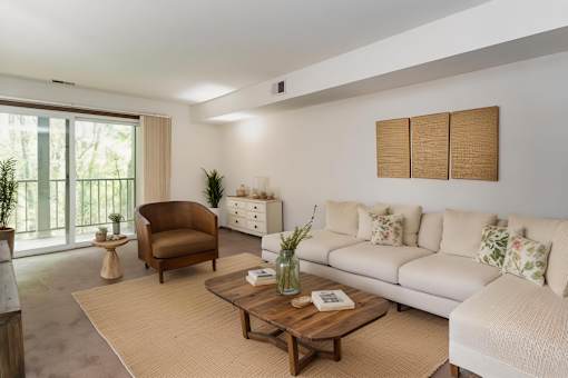 A living room with a white couch, a brown armchair, and a wooden coffee table at Winchell Way Apartment , Kalamazoo, 49008