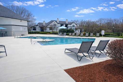 A pool with a few chairs around it.