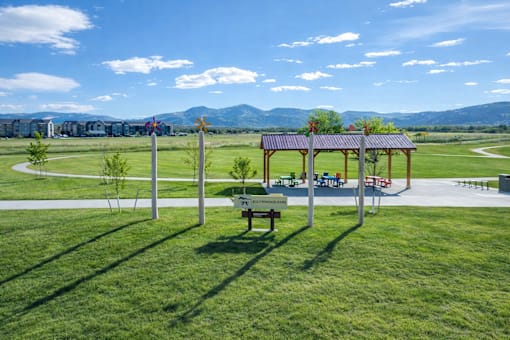 A park with a gazebo, picnic tables, and a signpost.
