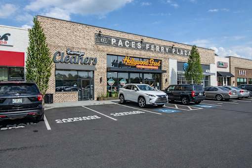 A parking lot with cars and a building with a sign that says "Paces Ferry Plaza".