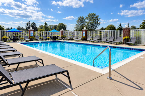 A pool surrounded by lounge chairs and umbrellas.