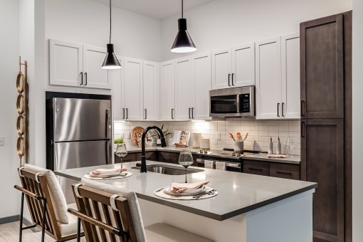 an open kitchen with a center island and a stainless steel refrigerator