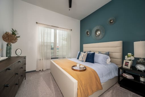 a bedroom with a bed and a blue wall and a window