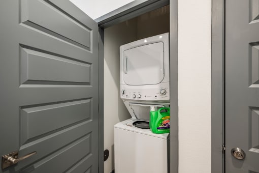 a small laundry room with a white washer and dryer and a gray door