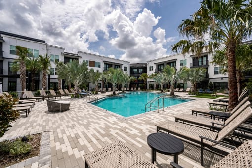 a swimming pool with palm trees in front of apartment buildings