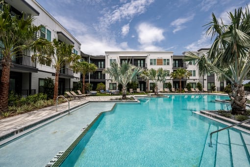 a large swimming pool with palm trees in front of apartment buildings